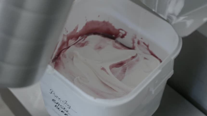 A person mixes ice cream and pours chocolate in