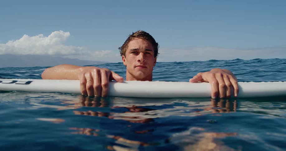 Man in the ocean holds a surfboard