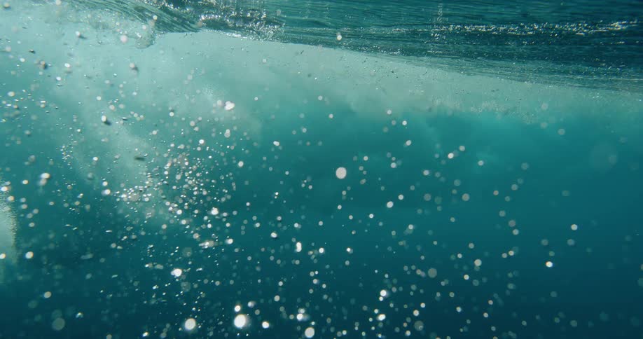 Bubbles float up underwater after a wave crashes