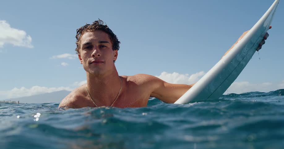 Young man floating on the sea over a surf board outdoors during day time