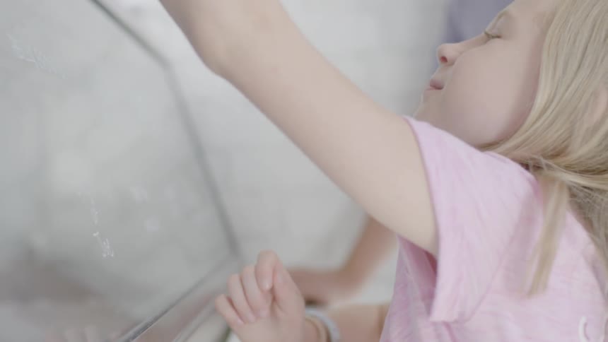 A young girl looks at ice cream flavors and tastes a sample