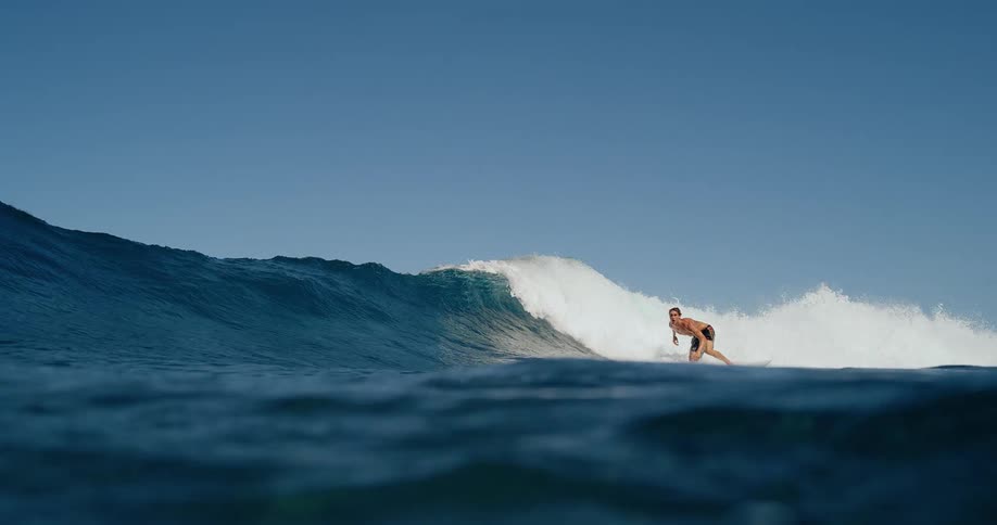 A surfer skillfully rides a powerful curling wave before the camera plunges underwater capturing the turbulent bubbly aftermath from below the surface
