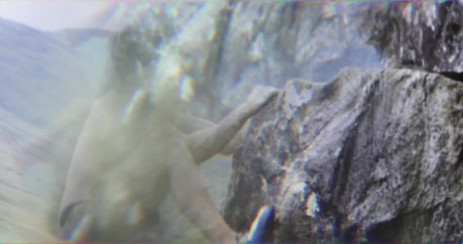A diver in a black swimsuit is shown leaping from a high diving board into a pool the shot is taken from underwater and bubbles and a burst of light are visible as a persons legs pass by