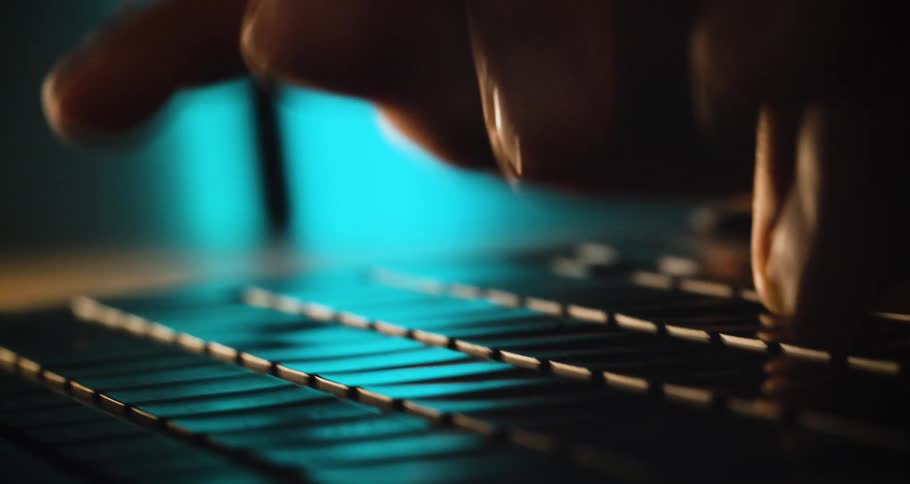 The first line shows a person typing quickly on a keyboard in a dimly lit room the second line shows a closeup shot of someones hands rapidly moving over the keyboard as blue light illuminates the keys