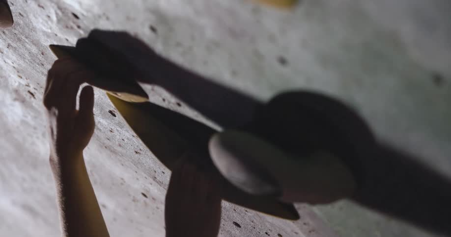 A persons hand searching for hand holds on a concrete climbing practice wall