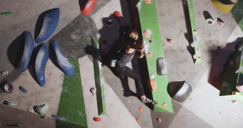 The woman is climbing the indoor rock climbing wall