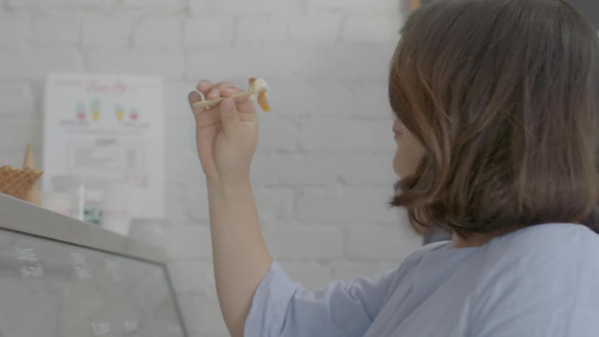 A woman tastes a sample in an ice cream parlor