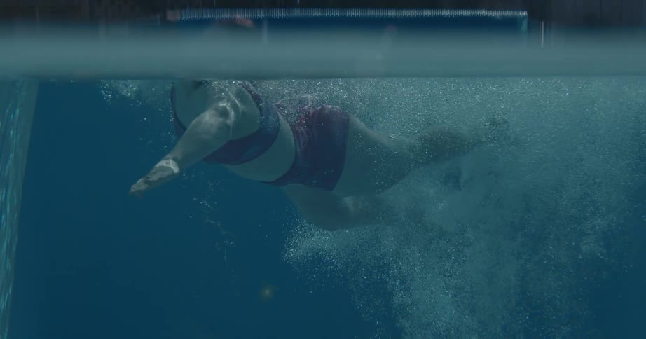 The first line is an underwater shot of a person doing a flip turn in a swimming pool kicking off the wall to push forward the second line shows the swimmers legs as they continue to propel through the water creating bubbles and movement