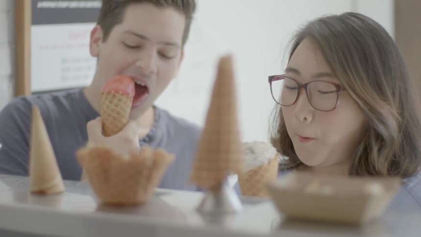 A person puts ice-cream into a cone and hands it to a customer