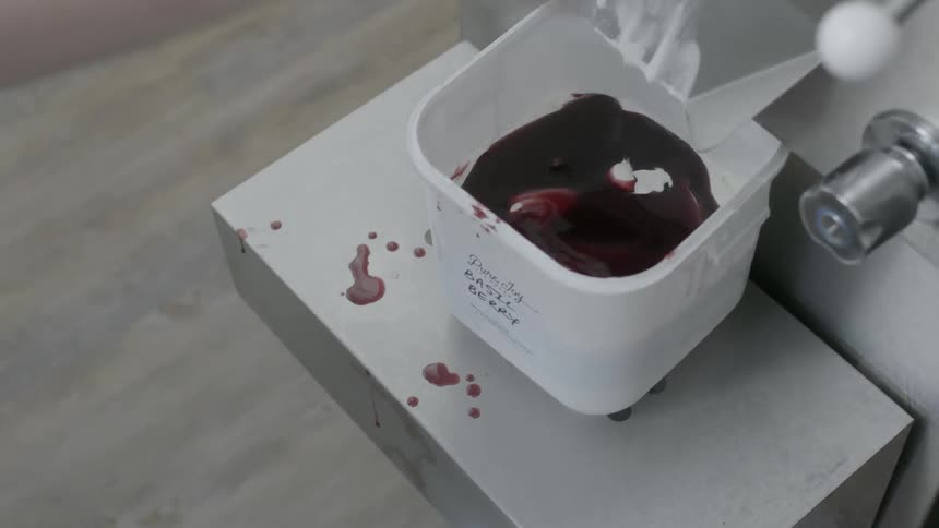 A person pours chocolate sauce in a machine