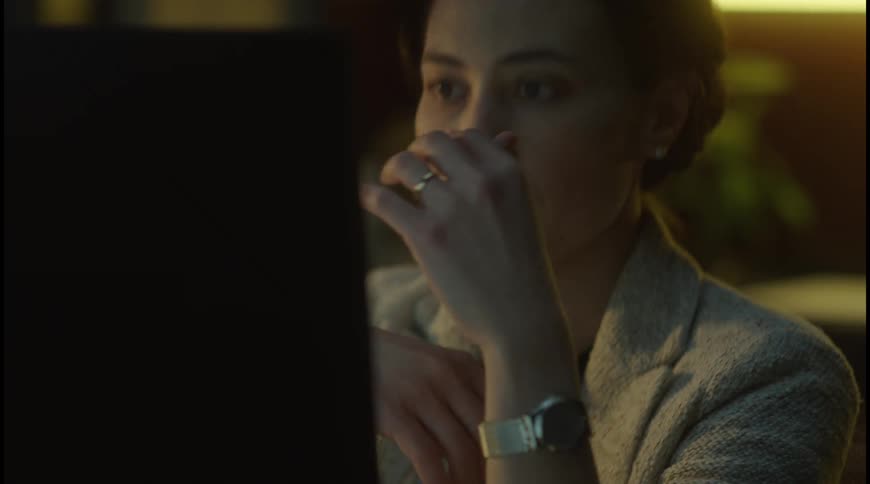 The woman puts on her glasses while using the computer