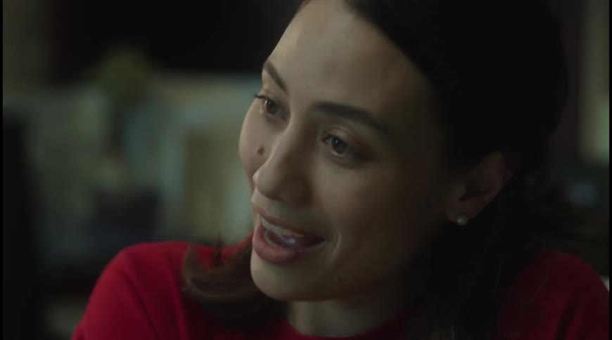 Woman in red smiles slightly in a work environment