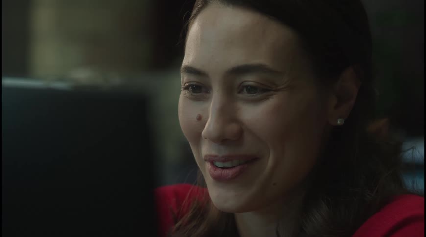 A medium closeup shot focuses on a persons face who appears to be reacting to something on a screen their expression shifts from a wide smile and laughter to one of surprise and then back to a smile