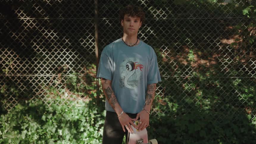 Portrait of a young man holding a skateboard in a park