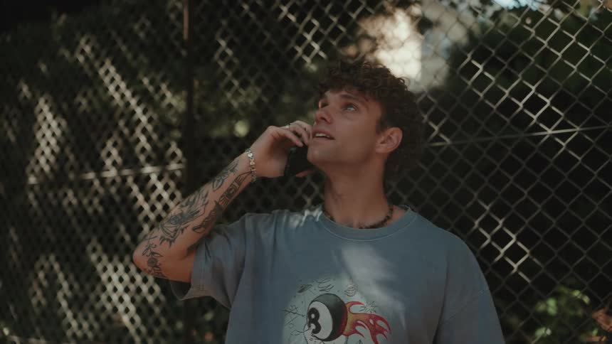 Tattooed young man outdoors talking on a phone
