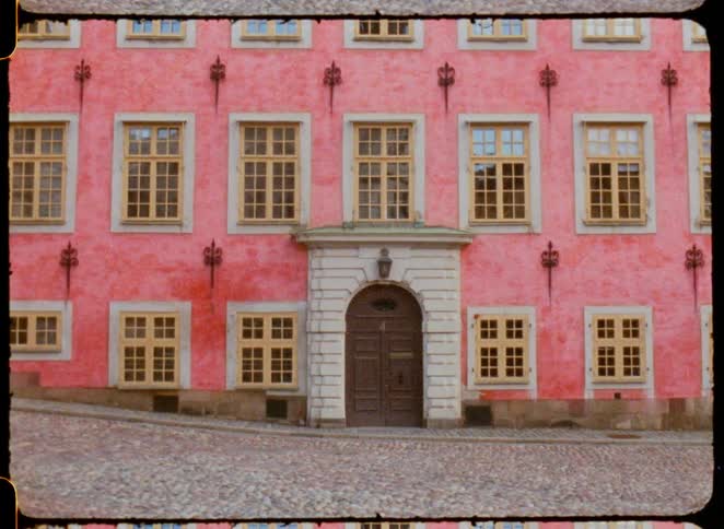 A large pink building on a cobblestone street