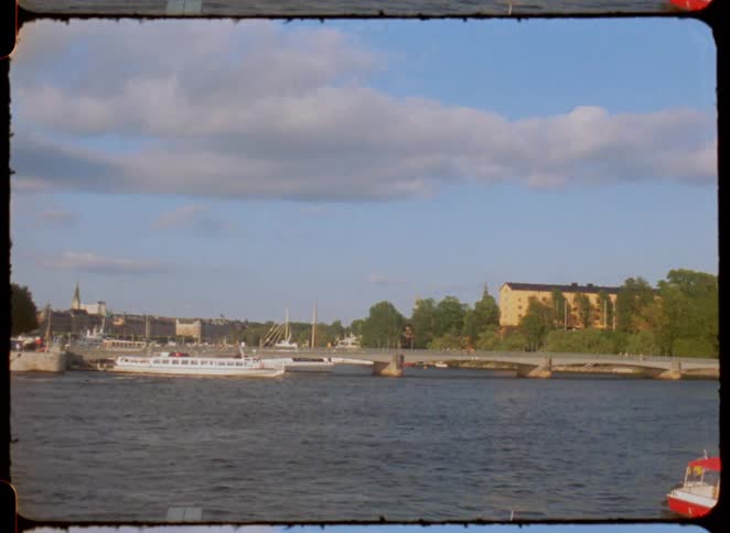 Boats sail on a river with a bridge and historic buildings in the background