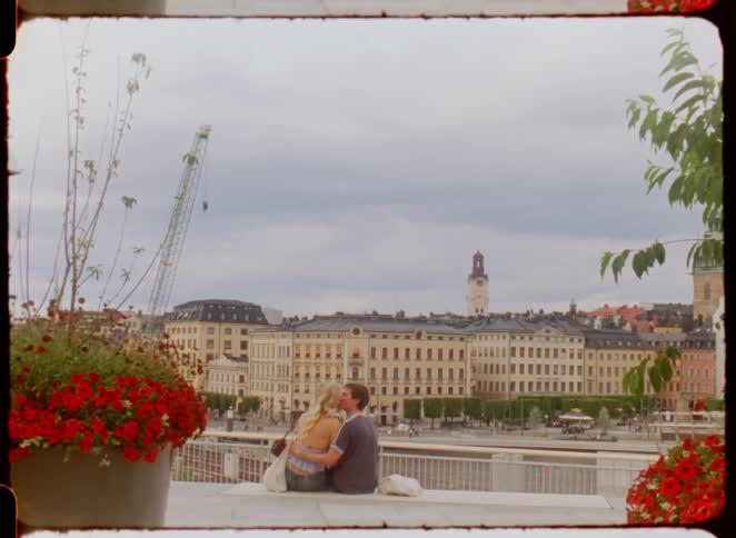Couple sitting at a viewpoint overlooking historic buildings and a tower in the background