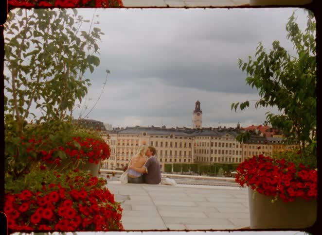 A couple kiss while sitting on the steps outside