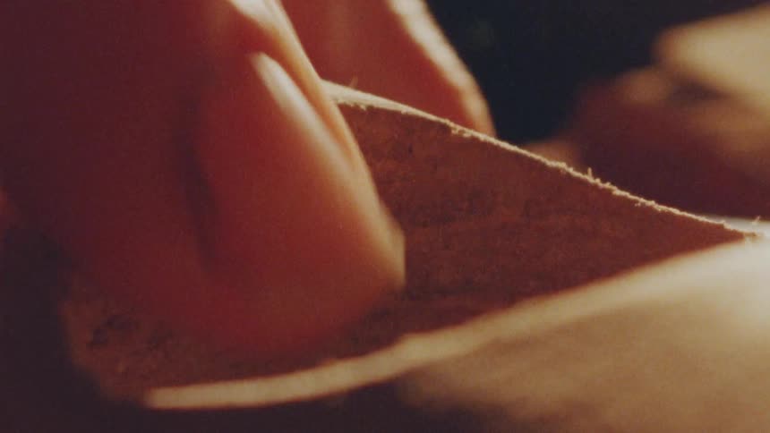 Man working on wood by cleaning up a hole on it with his fingers indoors