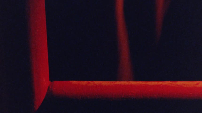 A persons feet with sandals stands in front of a red light that shines on the ground