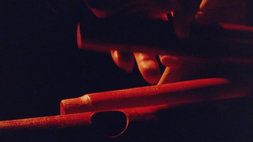 Fingers lit in red touch wooden pipes