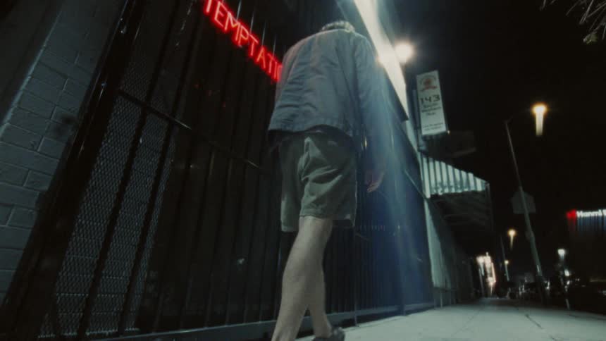 Two people walking on the sidewalk of a city street at night