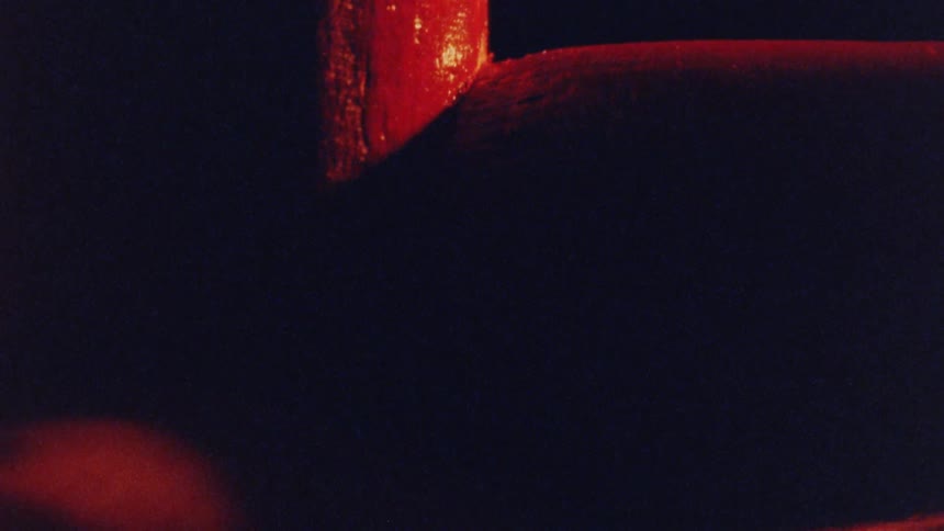 A close up of a red pieces of wood locking in a dimly lit environment