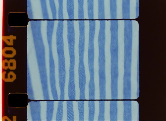 A section of film shows a blue and white striped fabric pattern moving in and out of focus within the rectangular frame bordered on the top and bottom by horizontal film black bars