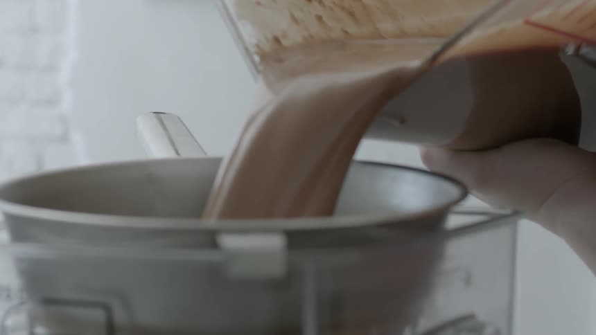 A woman is pouring a large container into a pot