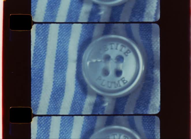 A section of a film strip with rounded corners shows a close view of a white button with the words petite plume on a blue and white striped shirt