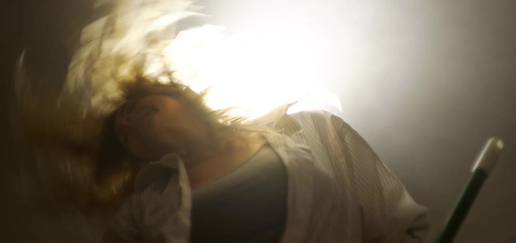 Woman dancing and headbanging while holding a cleaning utensil in her hand indoors