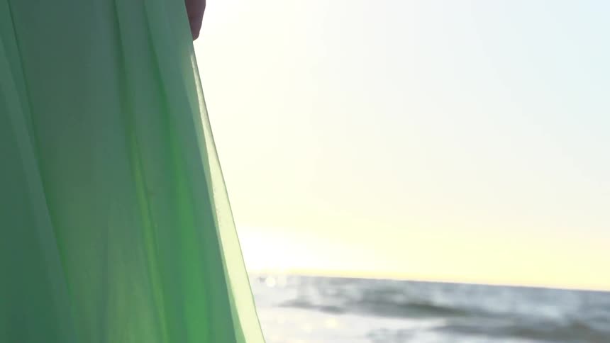 Ocean waves wash up onto a long, flowing dress