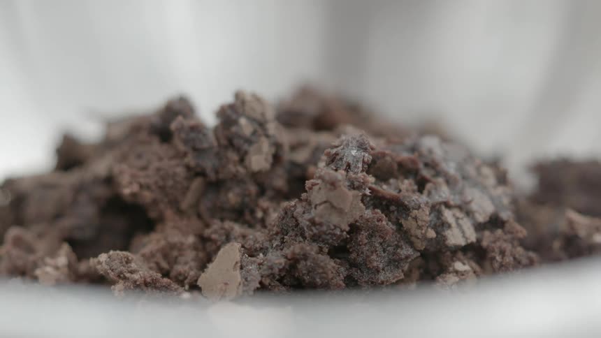 Pieces of chocolate are being dropped into a container