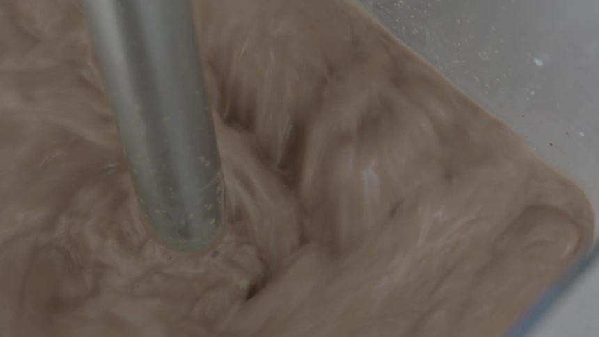 Milk is mixed in a container by a blender
