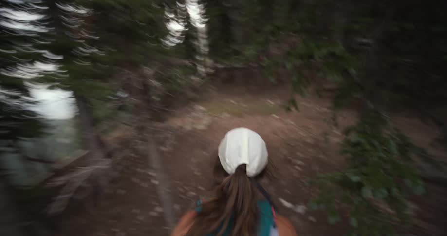 Point of view woman running on a trail through the forest
