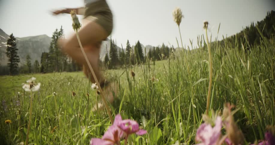 Person running in a grassy field with wildflowers