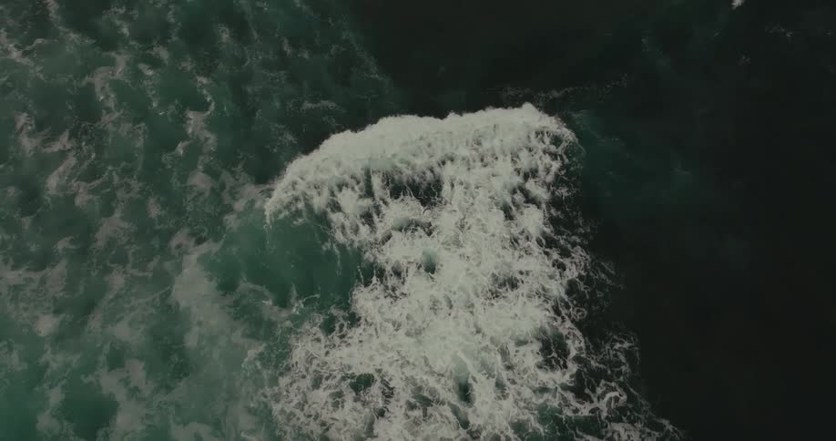 Birds eye view of wave rolling across middle of ocean