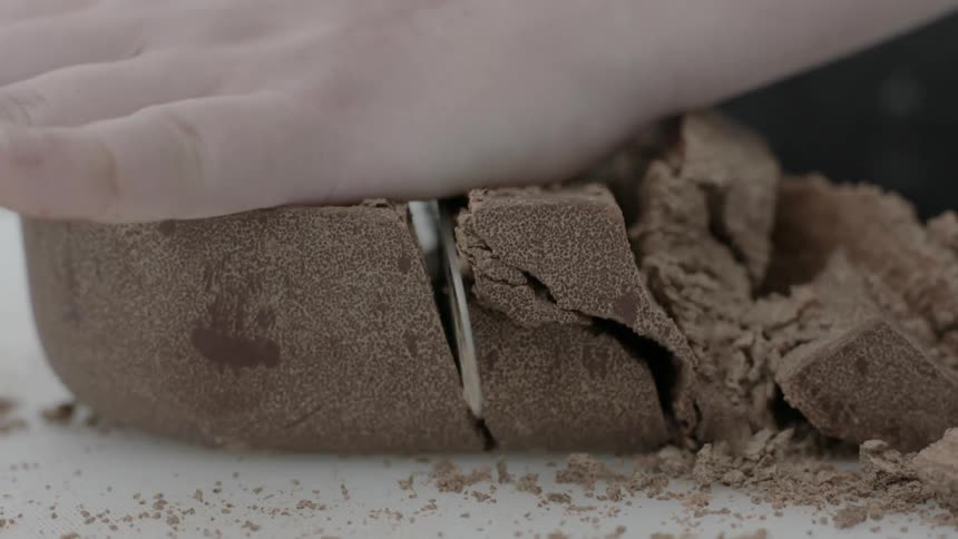 A person is cutting up chocolate with a large blade