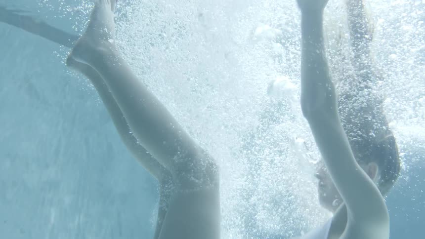 Woman falling into a pool wearing a white bathing suit