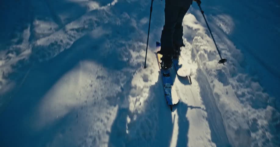 Person walks in the snow with trekking poles and a backpack