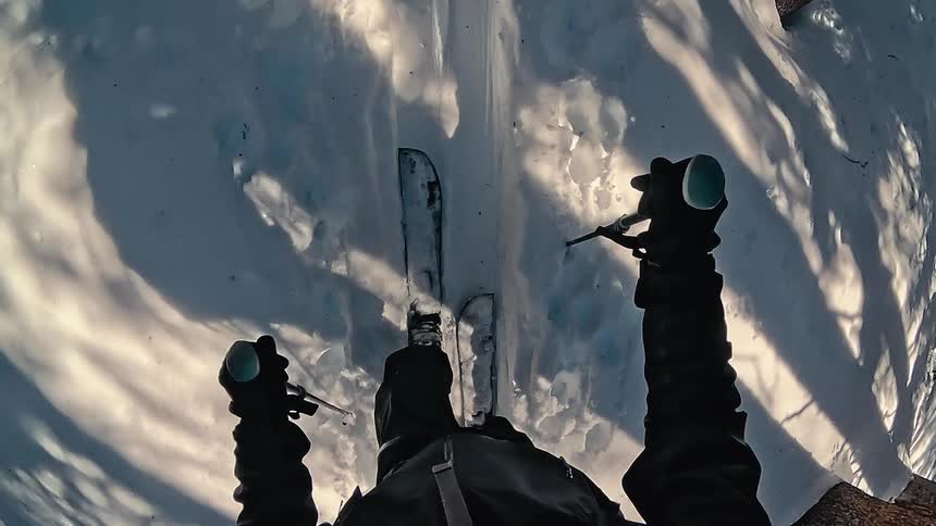A person skis on a snowy trail viewed from a firstperson perspective