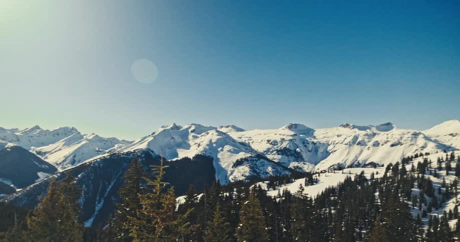 Snow covered mountain tops with forest trees and ski tracks
