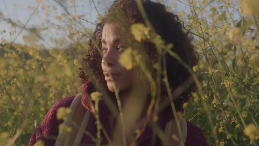 Close up portrait of a young black woman standing in a garden during daytime