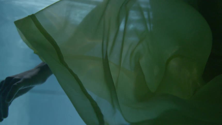 A woman is in the water wearing a long yellow dress