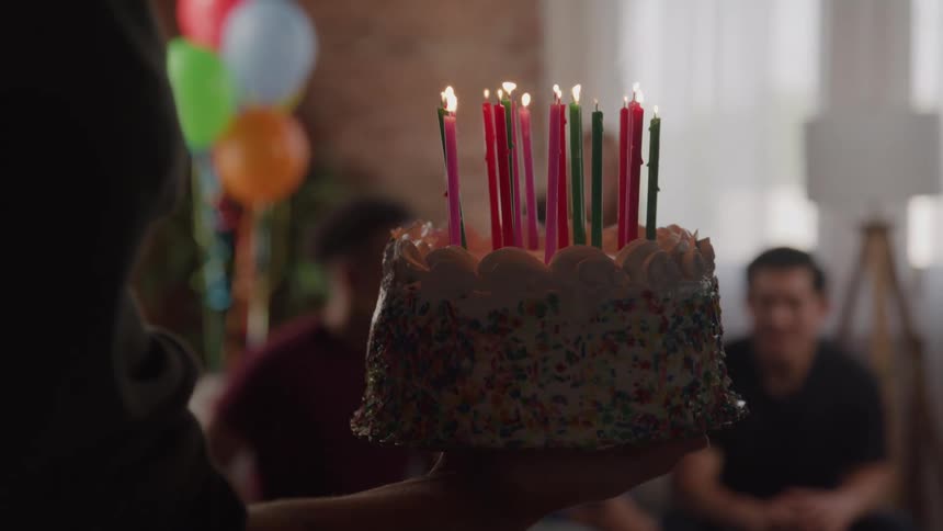 The birthday cake is carried into the party