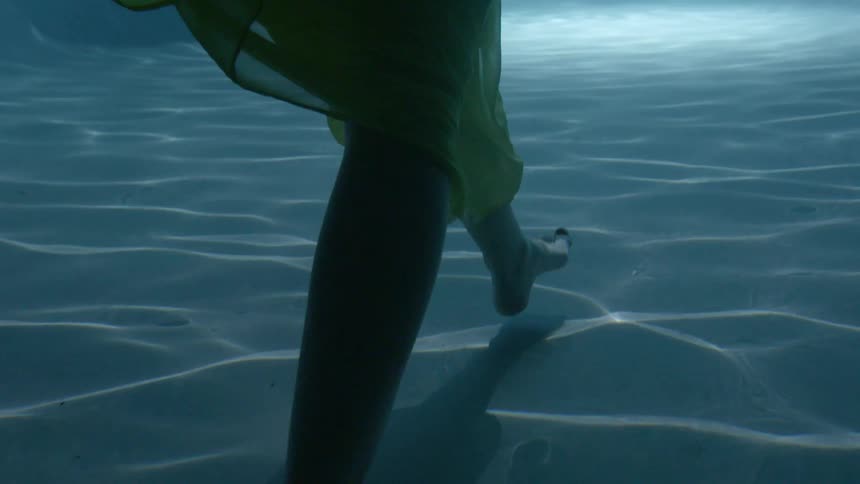 A woman is walking in the water wearing a dress