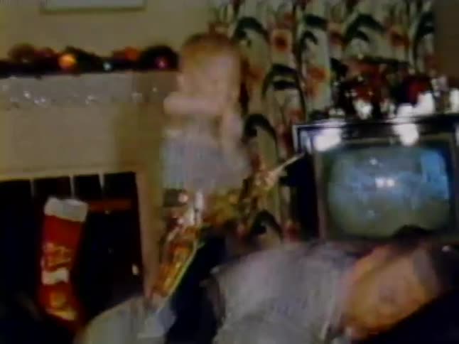 A boy is riding his father like a horse swinging a toy gun around