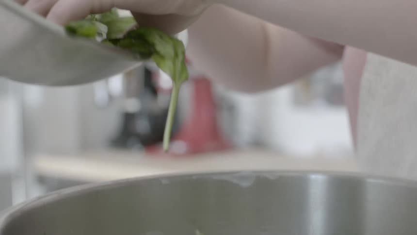A person pours vegetables in a pot