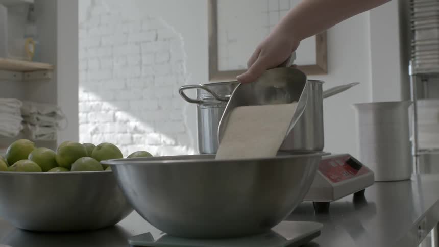 Man dumps sugar from a scoop into a mixing bowl